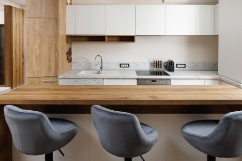 a kitchen with a counter with three chairs in it at Skylark Central Aparthotel in Braşov