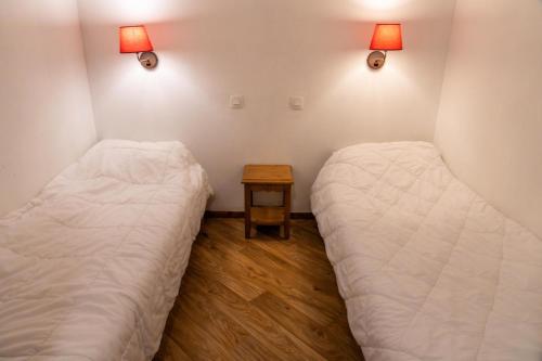 - 2 lits dans une chambre avec une table de chevet dans l'établissement Résidence Les Hauts De Preclaux - Studio au coeur des Orres 1800 MAE-9591, aux Orres