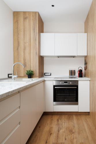 a kitchen with white cabinets and a sink and a stove at Skylark Central Aparthotel in Braşov