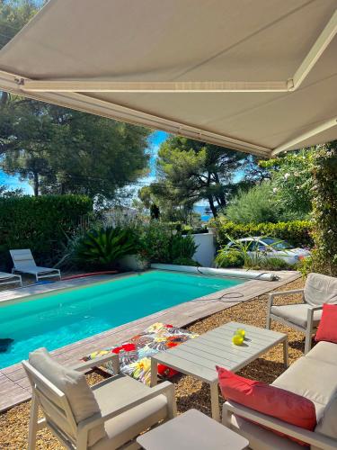 - une piscine avec une table et des chaises à côté de la piscine dans l'établissement Villa de charme avec piscine à proximité des plages, à Saint-Raphaël