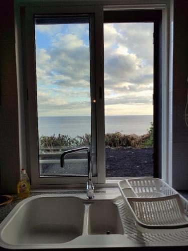 a kitchen sink and a window with a view of the ocean at Casa do Moinho in Lajes do Pico