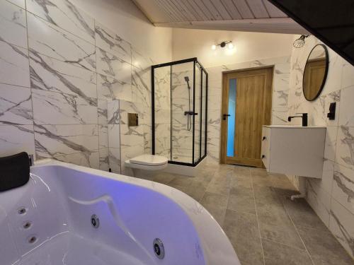 a white bathroom with a tub and a toilet at Apartament z prywatna wanną hydromasaż - U Parów in Białka Tatrzanska