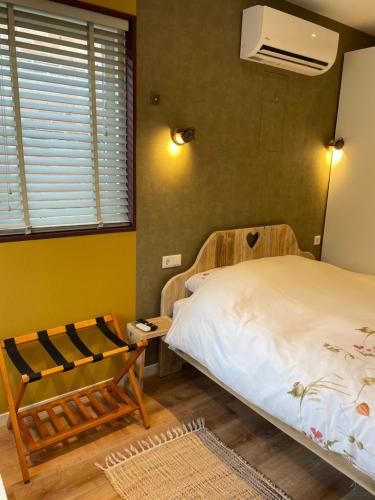 a bedroom with a bed and a chair and a window at Bed & Breakfast Danina in Sassenheim