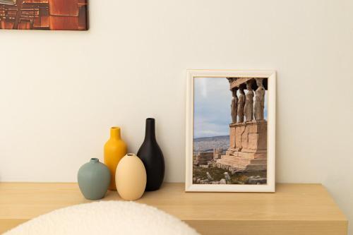 a table with vases and a picture on a wall at Elegant Apt 50meters Close Acropolis in Athens