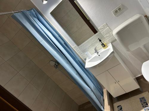 a bathroom with a blue shower curtain and a sink at Casa Natalia in Chişcău