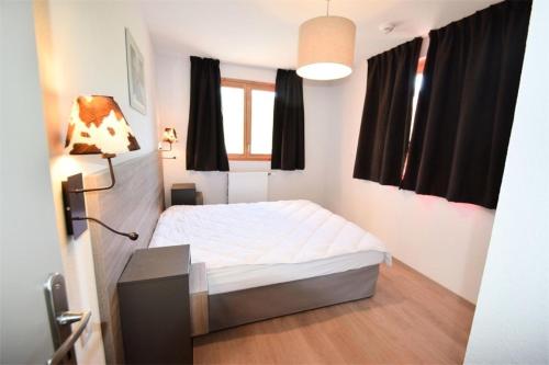 - une chambre avec un lit blanc et des rideaux noirs dans l'établissement Résidence Front De Neige - 3 Pièces 6 pers LE FRONT DE NEIGE - WIFI PLAGNE VILLAGES MAE-9384, à Aime La Plagne