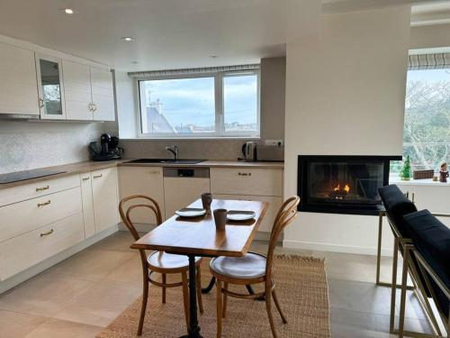 une cuisine avec une table et des chaises ainsi qu'une cheminée dans l'établissement Ker Agak Maison vue mer panoramique pour 7 pers, à Plougasnou