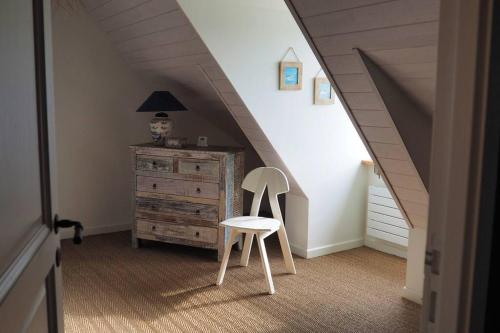 a chair in a room with a dresser and a staircase at Ker Agak Maison vue mer panoramique pour 7 pers in Plougasnou