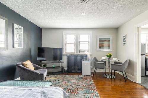 ハミルトンにあるModern Apartment on James St Southのリビングルーム(テレビ、テーブル、椅子付)