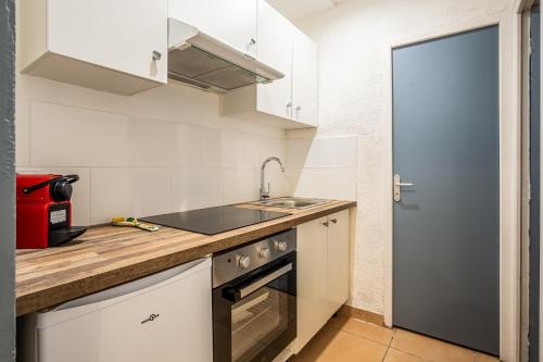 une petite cuisine avec un évier et une cuisinière dans l'établissement Le Cocon Urbain, à Narbonne