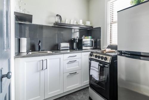 a kitchen with white cabinets and a black stove top oven at Modern Apartment with Kitchen on James St in Hamilton