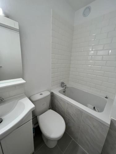 a white bathroom with a toilet and a bath tub at Charm studio nearby La Défense Arena in Puteaux