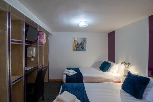 a hotel room with two beds and a television at OYO The Bentleys Hotel in Newcastle upon Tyne