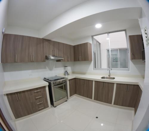 a kitchen with wooden cabinets and a sink at Hotel La Libertad - Ayacucho in Ayacucho