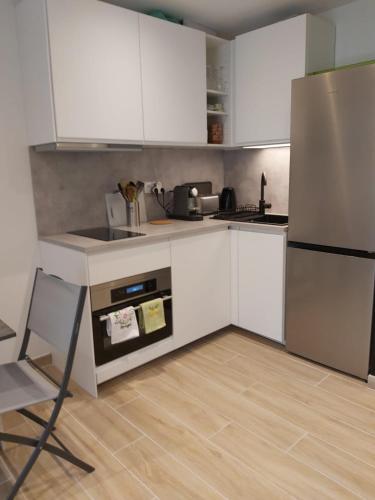 une cuisine avec des armoires blanches et un réfrigérateur en acier inoxydable dans l'établissement Studio climatisé, parking, 5mn de la plage, à Saint-Cyr-sur-Mer