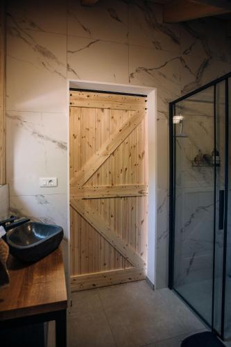a bathroom with a wooden door and a sink at Štajerska sivka - Jacuzzi & Savna in Maribor