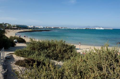 a beach with people on the sand and the water at Calas Beach Corralejo in Corralejo