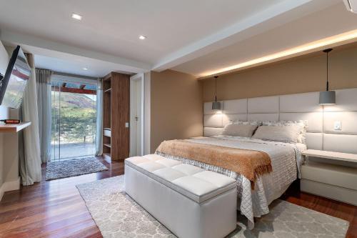 a bedroom with a large white bed and a window at Casa Bellavista, 4 suítes A/C, Sauna, Vista in Petrópolis