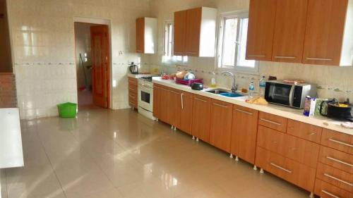 a large kitchen with wooden cabinets and a microwave at Brufut Heights Apartment in Brufut