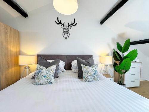 1 dormitorio con cama con almohadas y cabeza de ciervo en la pared en Nordic Suites Apartments, Ulverston, en Ulverston
