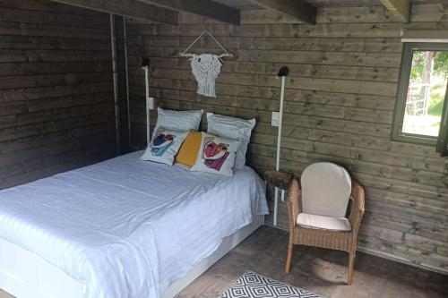 - un lit avec des oreillers et une chaise dans la chambre dans l'établissement Chalet en Ardèche, à Fabras