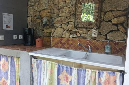 een keuken met een wastafel en een stenen muur bij Chalet en Ardèche in Fabras