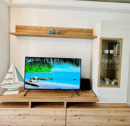 a flat screen tv sitting on a wooden entertainment center at Bonito apartamento con piscina a 50 metros de la playa! in Port de Pollensa