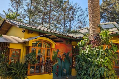 a yellow house with a palm tree in front of it at Chalet La Llovizna - Lush hidden paradise in Panajachel in Panajachel