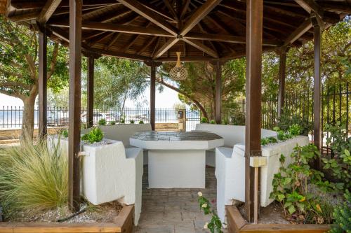 a wooden gazebo with a table and some plants at Alkis Guest House by AegianKazarte in Kapótidhes