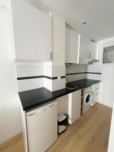 une cuisine avec des armoires blanches et un comptoir noir dans l'établissement Le Stalingrad - Gare - Centre, à Toulouse