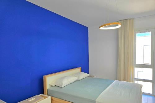 a blue bedroom with a bed with a blue wall at Swiss Sweet Apartment 297 - Happy Rentals in Lalzit Bay