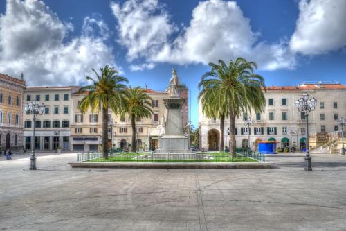 a large building with palm trees in front of a fountain at Baddi Di La Predda - Happy Rentals in Sassari