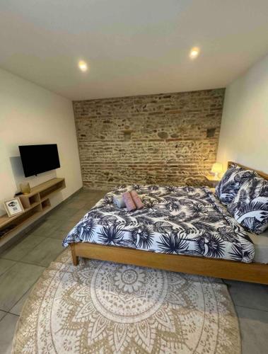 une chambre avec un lit et un mur de briques dans l'établissement Studio cosy avec fraicheur et confort, à Lescure-dʼAlbigeois