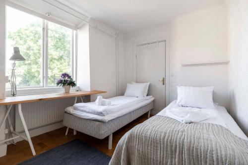 une chambre avec deux lits et un bureau et une fenêtre dans l'établissement Beautiful 3 bedroom apartment in heart of Visby, à Visby