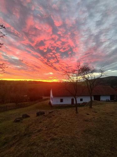 a sunset over a white barn in a field at Country house - Slapy/Pazderny in Žďár