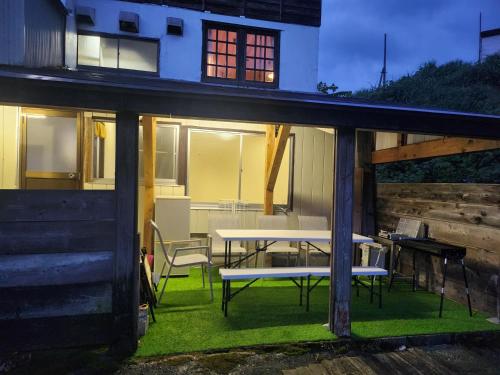 a house with a table and chairs on the grass at ロッヂノエル in Seki
