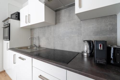 a kitchen with white cabinets and a sink at FarawayHomes Studio Fohnsdorf #11 in Fohnsdorf