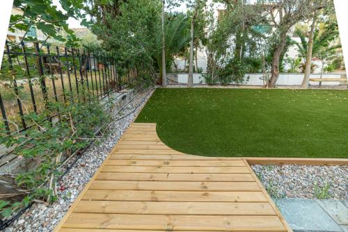 a garden with a wooden walkway and a green lawn at Alkis Guest House by AegianKazarte in Kapótidhes