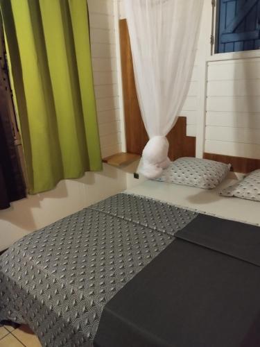 a bed in a room with green and white curtains at Le pain de sucre in Marigot
