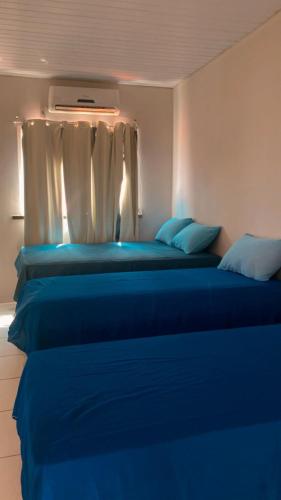 two beds in a room with blue sheets at Pousada Andrade in Parnaíba