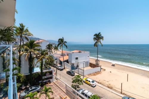 Blick auf einen Strand mit Palmen und ein Gebäude in der Unterkunft The Paramar Beachfront Boutique Hotel With Breakfast Included - Downtown Malecon in Puerto Vallarta