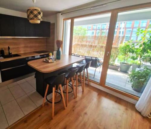 une cuisine avec une table et des chaises ainsi qu'une grande fenêtre dans l'établissement Appartement, à Saint-Denis