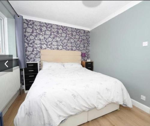 a bedroom with a bed with a floral accent wall at Entire cosy Apartment in a quiet lovely area with parking in Wellingborough