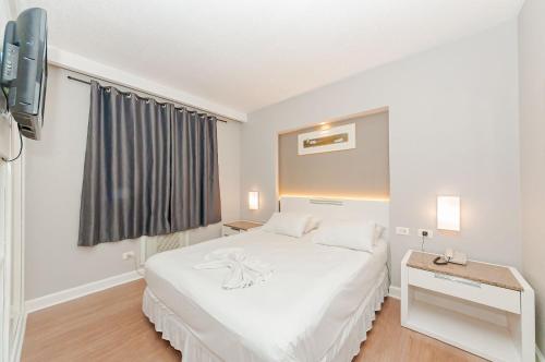 a bedroom with a white bed and a tv at Apto-Flat Excelente Localização Centro-Batel - Somente Familiares in Curitiba
