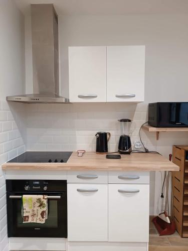 une cuisine avec des armoires blanches et un four à plaques de cuisson dans l'établissement Maison de ville vitry, à Vitry-sur-Seine