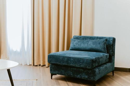 a blue chair sitting in a living room next to a window at Andor Luxury Hotel & Duplex in Durrës