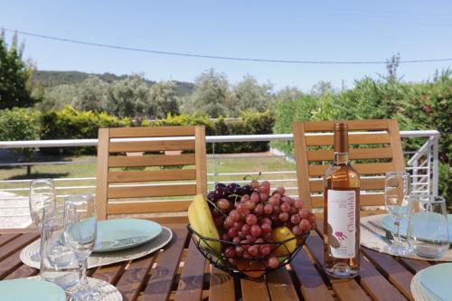 a table with a bowl of fruit and a bottle of wine at Toroneos Sea Side Villa in Paliouri