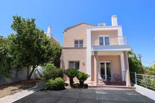 a large white house with a balcony and trees at Toroneos Sea Side Villa in Paliouri