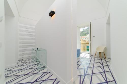 a hallway with white walls and white floors and a staircase at Palazzo Colavolpe Suite in Atrani