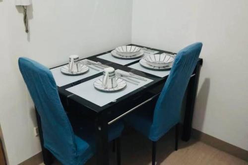 a black table with blue chairs and plates on it at E & R Staycation Condotel near Mall of Asia in Manila